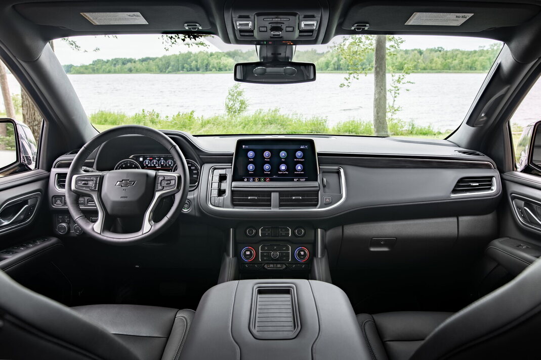 Foto interna do Chevrolet Suburban Premier 2024, exibindo parte do painel de instrumentos, volante multifuncional, central multimidia e parte dos bancos.