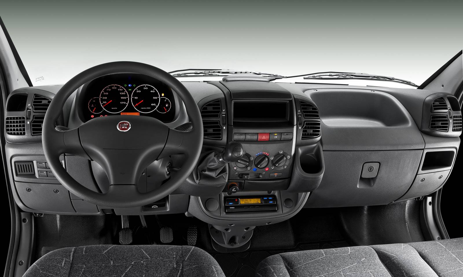 Foto interna do Fiat Ducato curto 2.3 2015, exibindo o painel de instrumentos, parte do console e dos bancos.