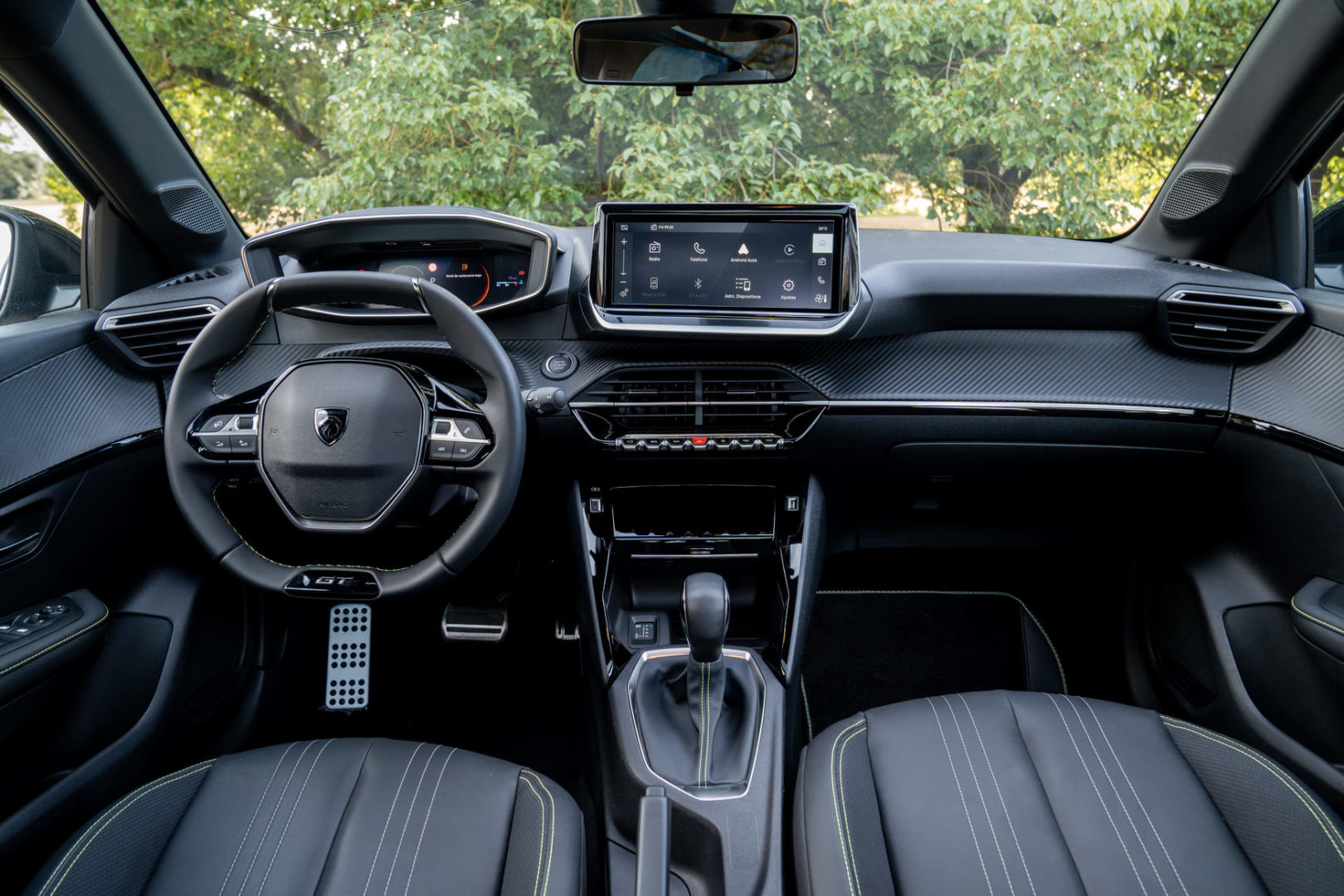 Foto interna do Peugeot 208 GT 2025, exibindo o painel de instrumentos digital, volante multifuncional e a central multimidia.