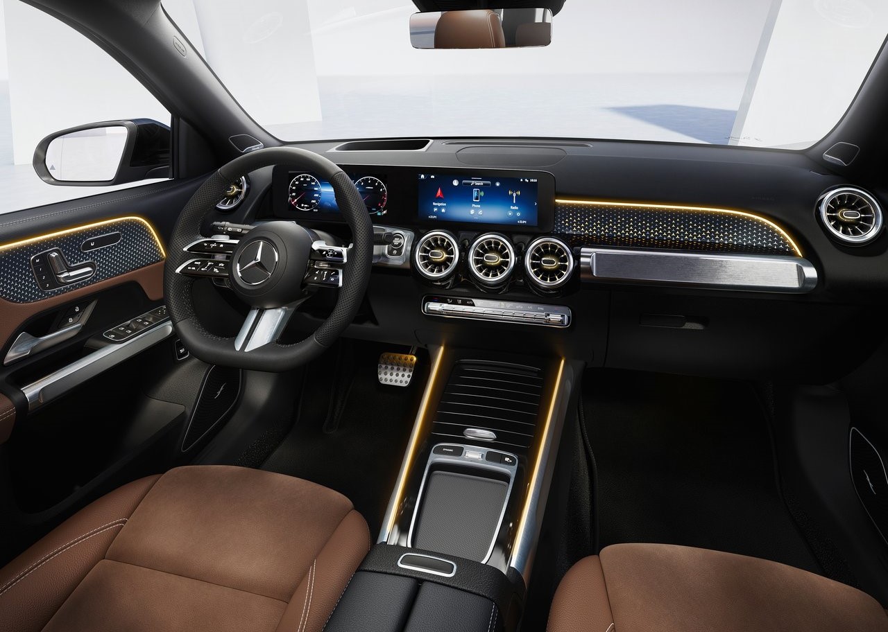 Foto interna do Mercedes-AMG GLB 2025, exibindo as duas telas de 10,25 polegadas, volante multifuncional, parte dos bancos e portas.