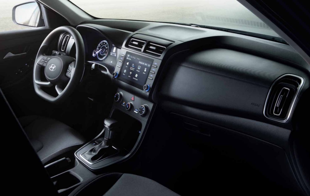 Foto interna do Hyundai Creta Comfort Plus 1.0 2025, exibindo o painel de instrumentos, volante multifuncional, central multimídia e parte dos bancos.