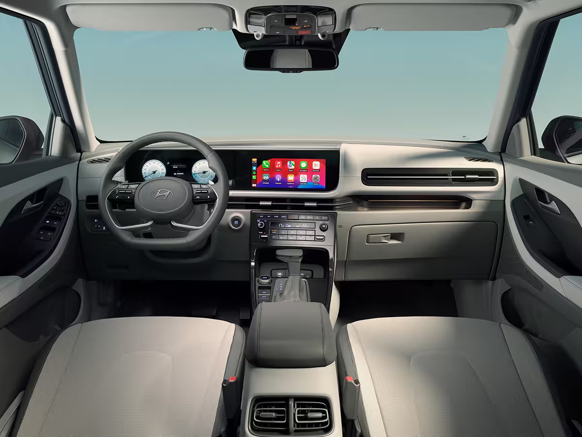 Foto interna do Hyundai Creta Platinum 2025, exibindo o painel de instrumentos digital, volante multifuncional, central multimídia, parte dos bancos e das portas.
