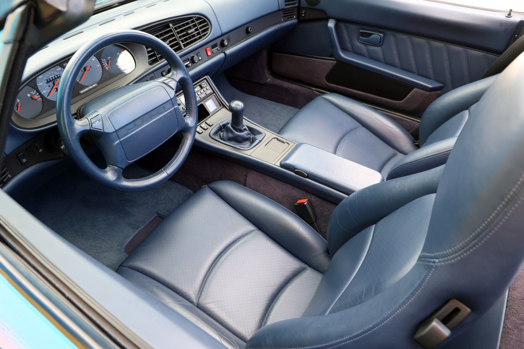 Foto interna do Porsche 968 Cabriolet (1991-1995), exibindo os bancos em couro, volante, painel de instrumentos e parte do console central.