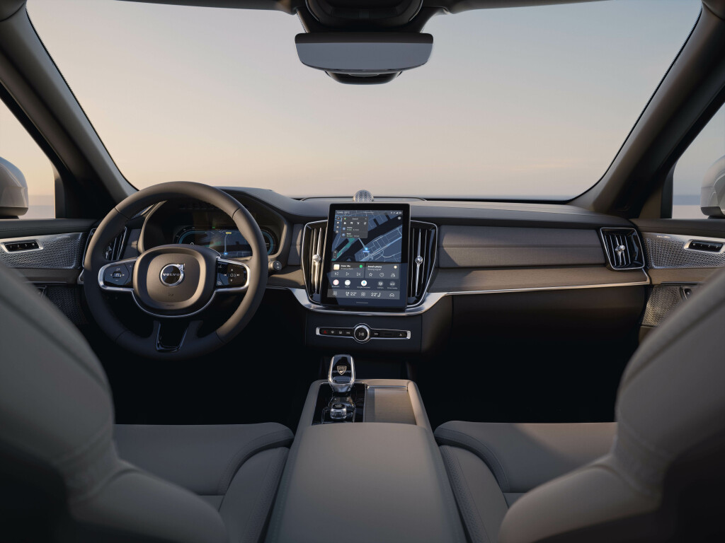 Foto interna do Volvo XC90 Ultra T8 2025, exibindo o painel de instrumentos, volante multifuncional, central multimídia, parte dos bancos e do console central.