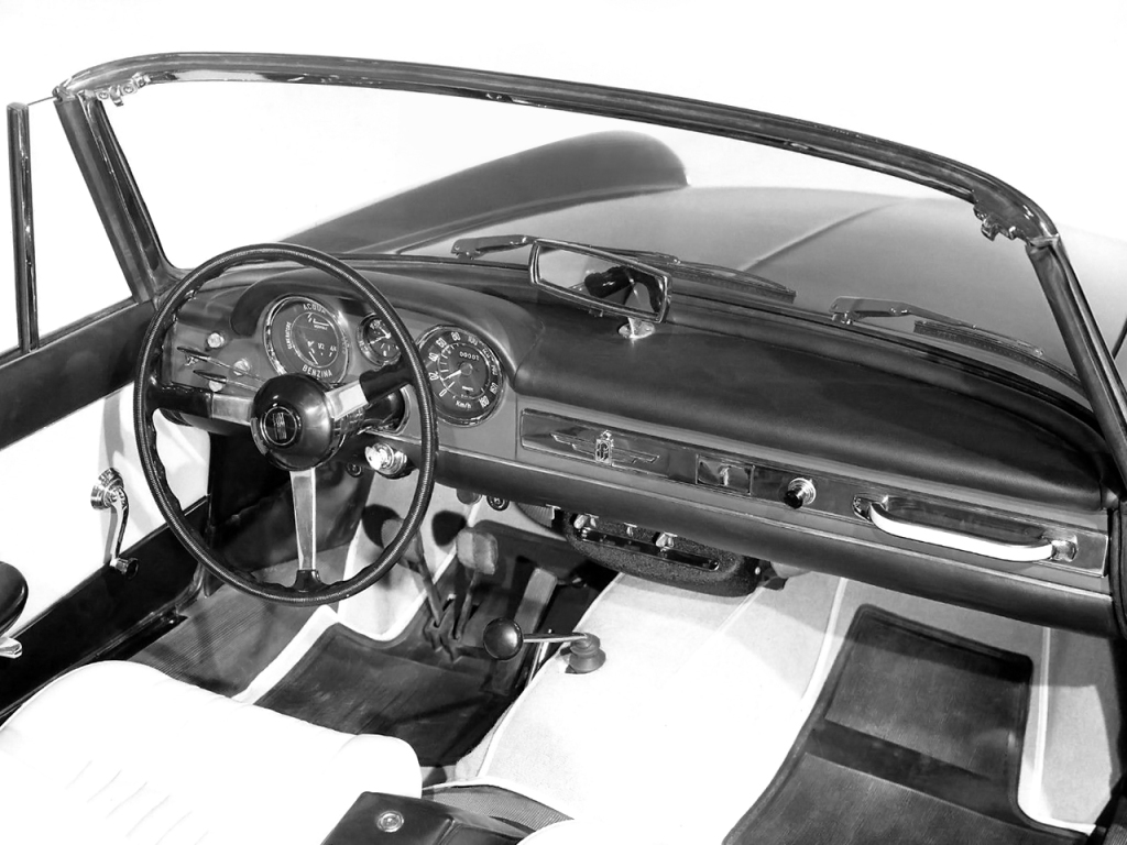 Foto interna do Fiat 1200 Cabriolet 1960, exibindo o painel de instrumentos, volante e parte dos bancos.