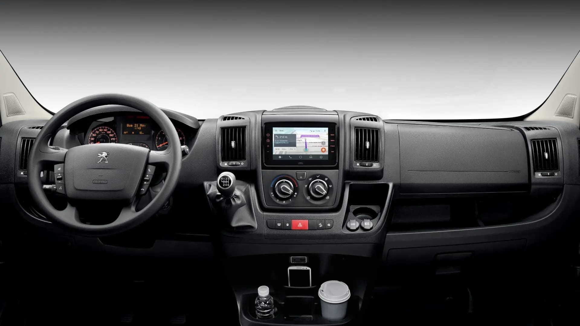 Foto interna do Peugeot Boxer Furgão 2025, exibindo o painel de instrumentos, volante multifuncional e a central multimídia.