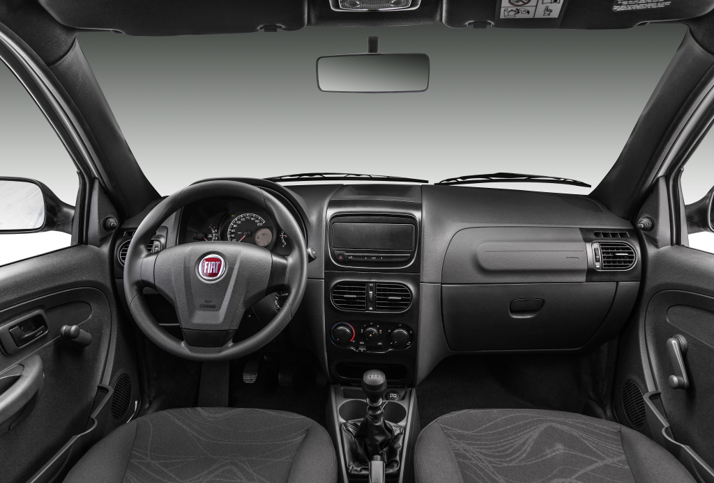 Foto interna do Fiat Strada Hard Working (2015-2020), exibindo o painel de instrumentos, volante, parte dos bancos e das portas.