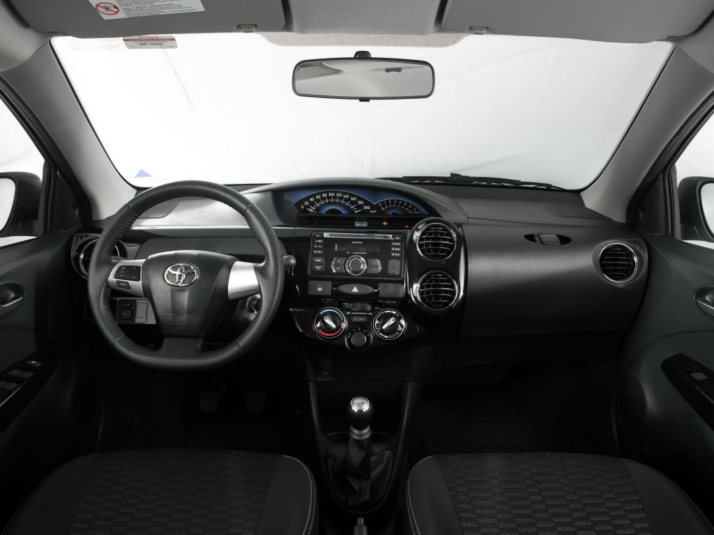 Foto interna do Toyota Etios Cross (2014-2017), exibindo o volante multifuncional, painel de instrumentos, central multimídia, parte dos bancos e das portas.
